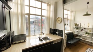 Cocina moderna con un ventanal grande, lavavajillas integrado y comedor con una silla negra.