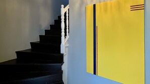 A staircase with white balusters, a chandelier, and a yellow artwork on the wall. - The Thirty8 Heritage House (Chania)