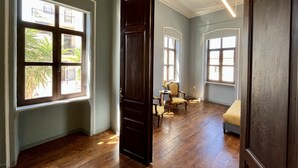 A room with wooden flooring, a large window, a door, and a chair. - The Thirty8 Heritage House (Chania)
