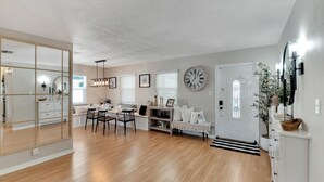 A modern living room with a dining area, a large clock, and a door with a window. - South Tampa Pool Home! (Tampa)