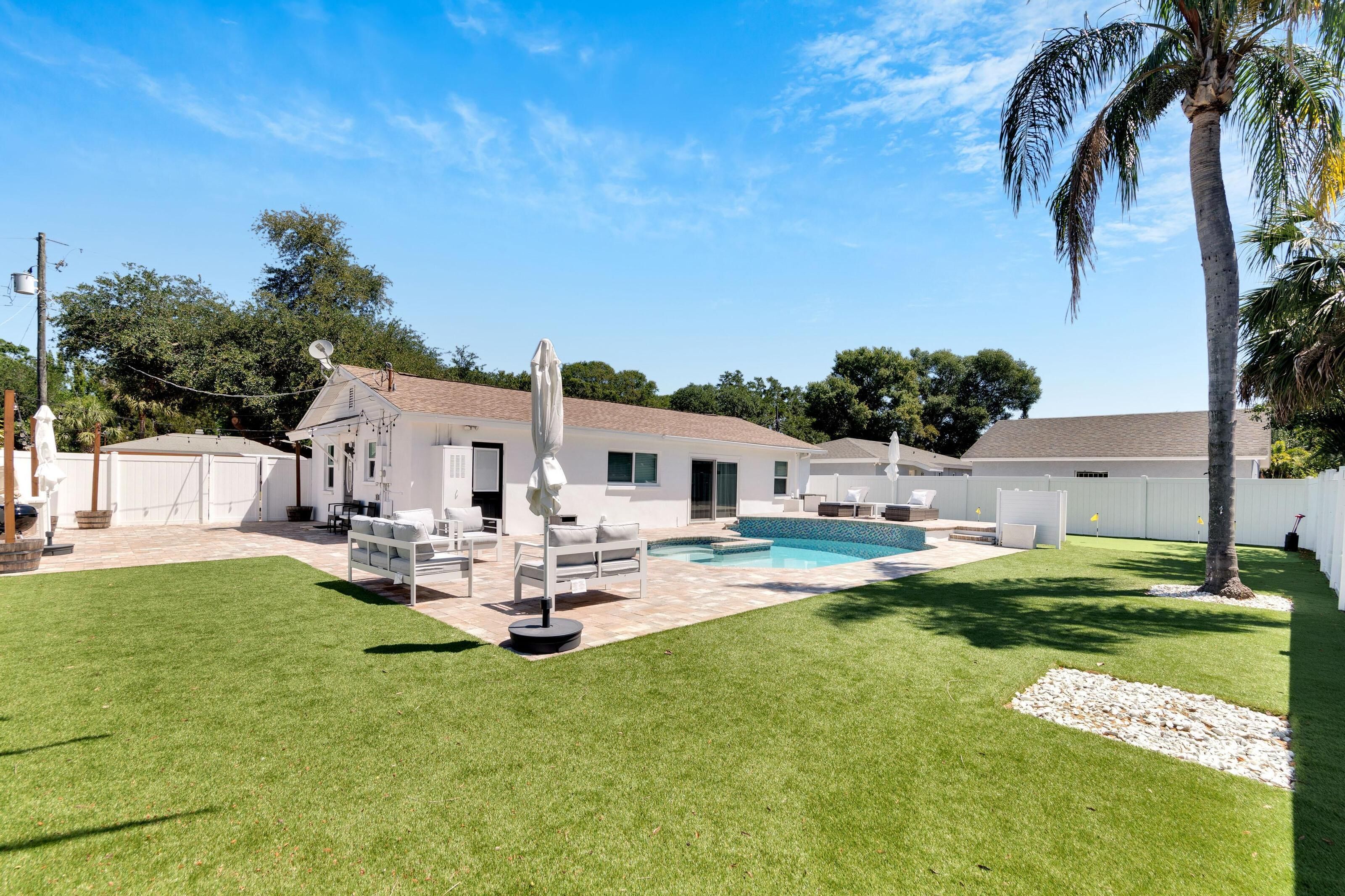 Uma casa moderna com piscina, fachada branca e gramado bem cuidado.