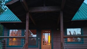 Un chalet en bois doté d’une véranda, d’une porte d’entrée et d’une enseigne indiquant l’adresse.
