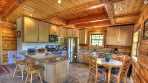 L’intérieur d’un chalet en bois comprend une cuisine, un coin repas et une grande fenêtre.