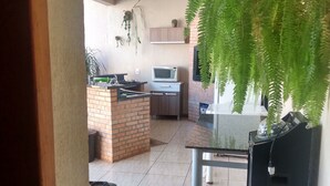 A modern kitchen with a microwave, stove, and hanging plants. - Edicula Foz (Foz do Iguaçu)