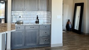 Une cuisine moderne avec des meubles gris, un plan de travail en marbre et un pare-feu en carrelage.