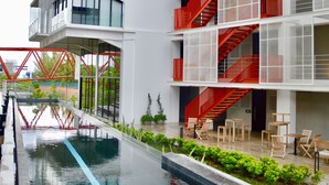 Un edificio moderno con varios balcones, piscina y zona de estar al aire libre.