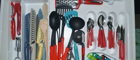 Un tiroir contenant divers ustensiles et outils de cuisine, notamment des ciseaux, des spatules et une râpe.