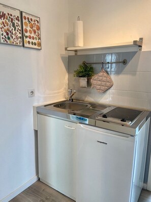 Una cocina compacta con lavavajillas empotrado, estufa y colgador para ollas.