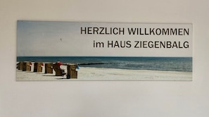 Escena de playa con un cartel que dice 'HERZLICH WILLKOMMEN im HAUS ZIEGENBALG'.