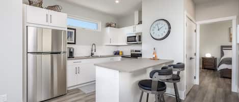 Una cocina moderna con una isla central, electrodomésticos de acero inoxidable y un reloj de pared grande.