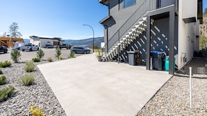Ein modernes Gebäude mit Betonauffahrt, einer Treppe mit geometrischen Mustern und einem Parkplatz mit mehreren Autos.
