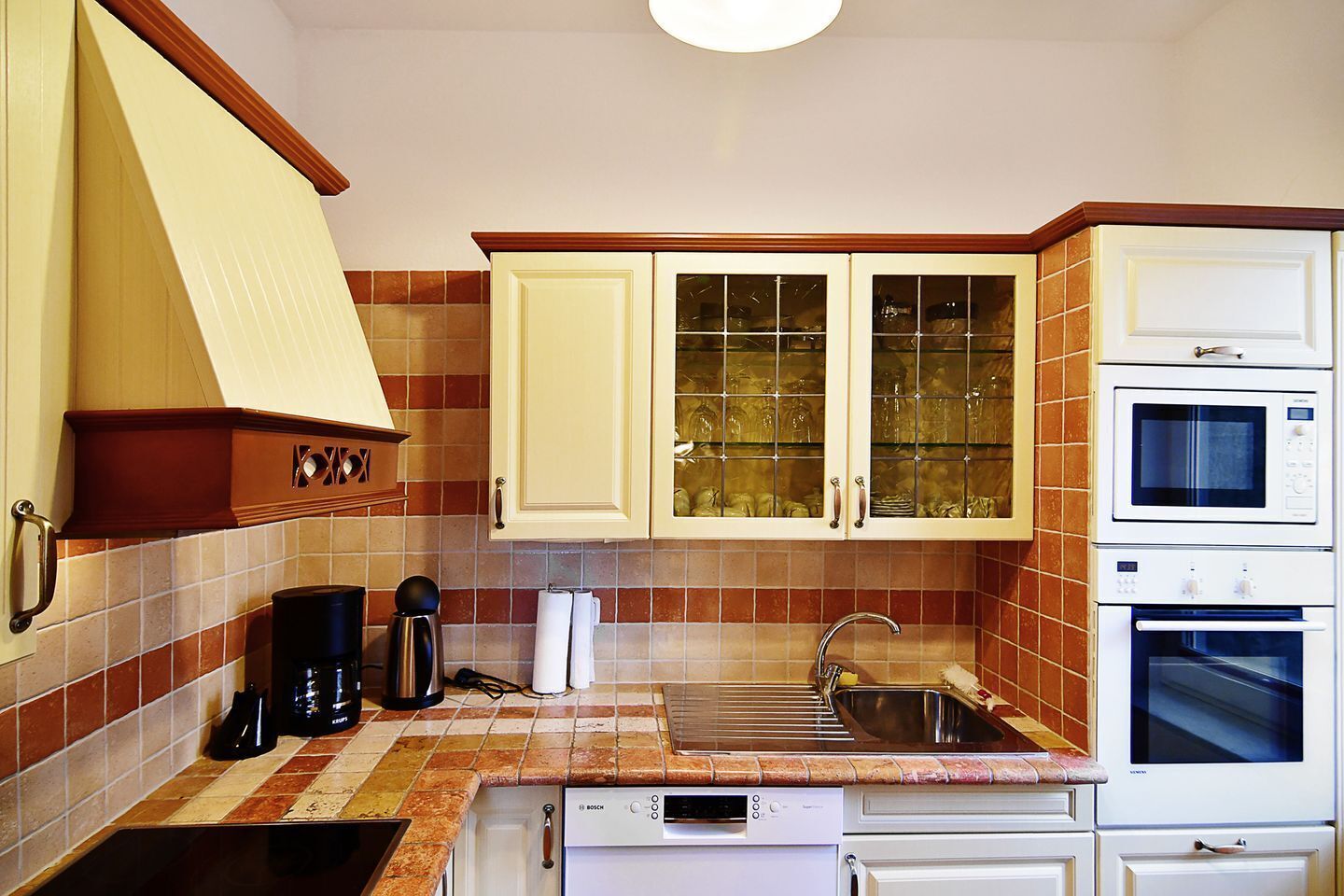 A compact kitchen with white cabinets, a built-in microwave, and a Bosch dishwasher.