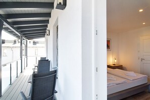 Une chambre moderne avec un lit, une table de chevet et une vue sur le balcon extérieur.