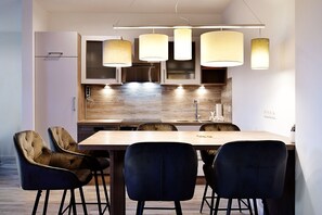 A modern kitchen with a wooden countertop, stainless steel appliances, and pendant lighting. There are four chairs around a dining table. - The house Ahlbeck - beautiful 80sqm - Remise (restored in 2023) - Villa (Heringsdorf)
