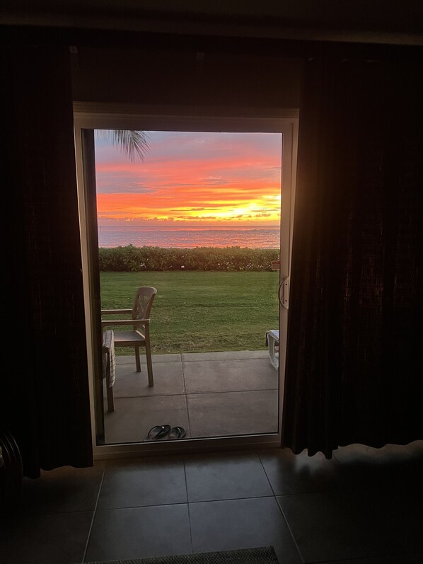 A doorway leading to a patio with a view of a sunset over the ocean.