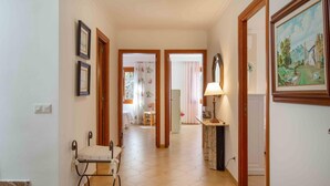 Un couloir avec une chaise, une lampe et un tableau accroché au mur.