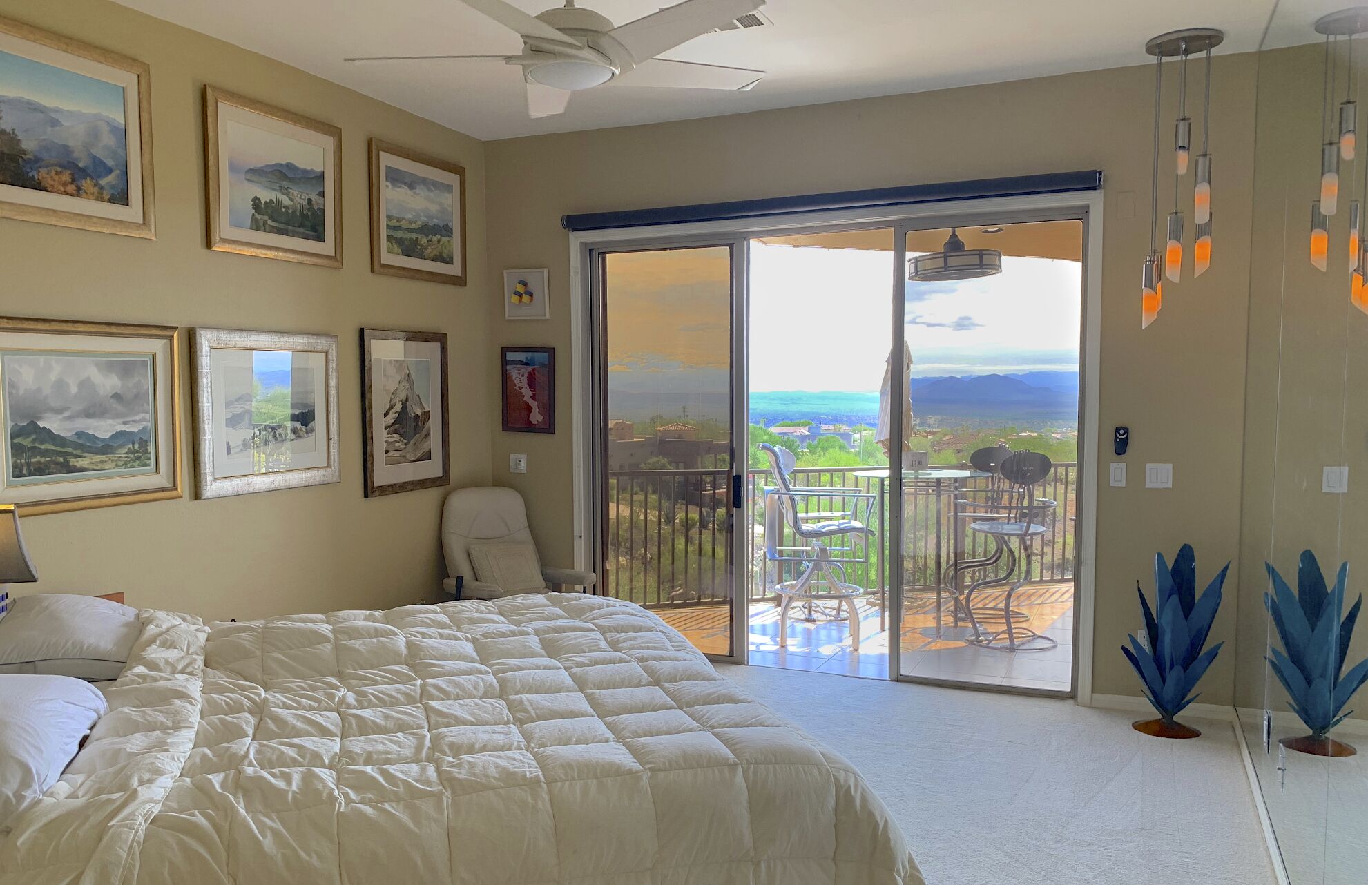 Ein Schlafzimmer mit einem großen Bett, einem Deckenventilator und Blick auf einen Balkon mit Gartenmöbeln.