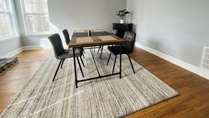 Un coin repas comprenant une table rectangulaire, six chaises, un tapis et une plante en pot.