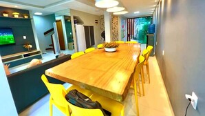 Un comedor moderno con una mesa de madera y sillas amarillas, un banco empotrado e iluminación colgante.