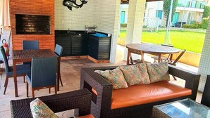 Un patio al aire libre con mobiliario de mimbre, una chimenea de ladrillo y vistas a una zona residencial.