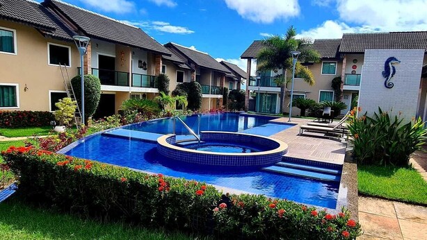 Edificio residencial con piscina, un pequeño jardín y una puerta visible.