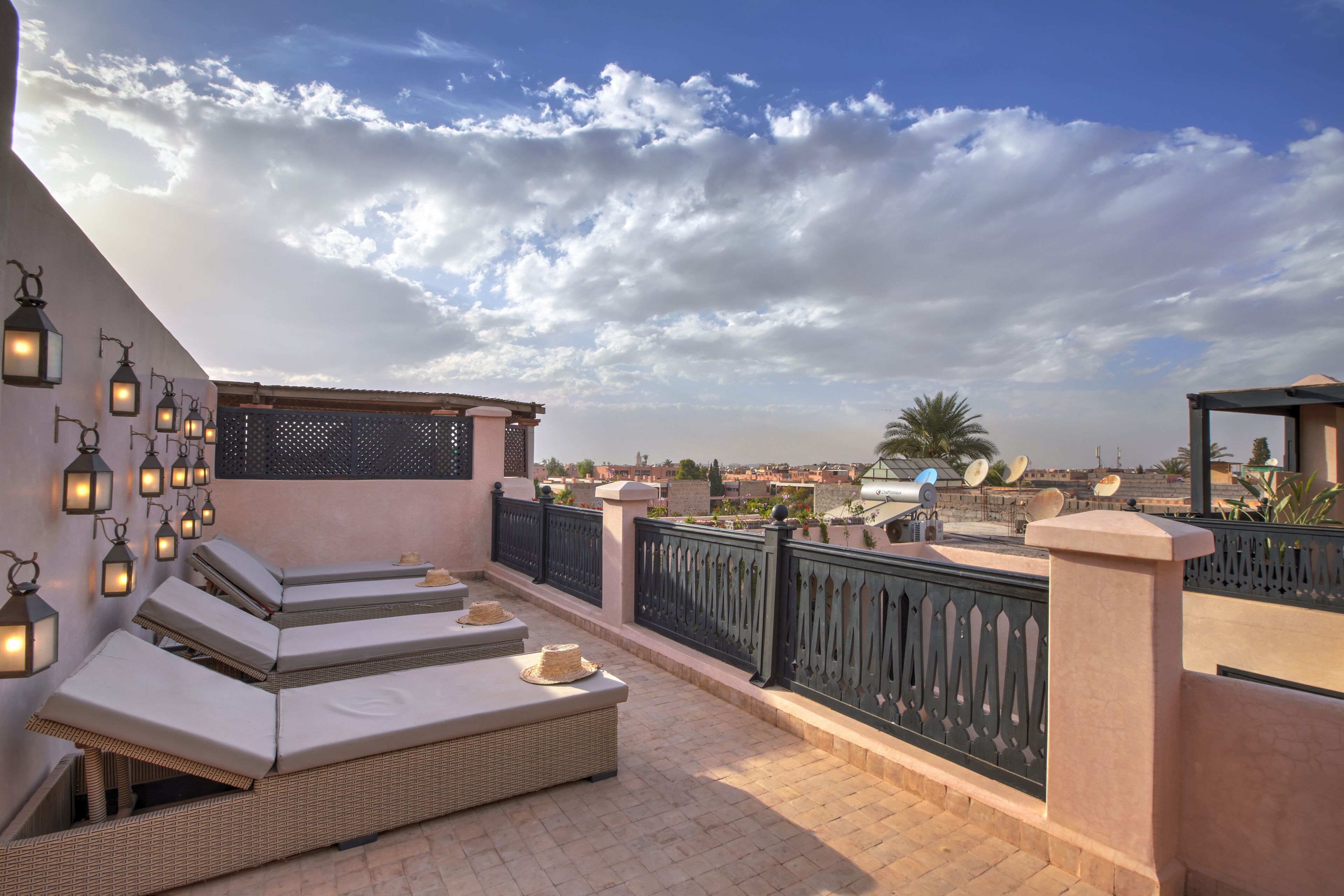 Una terrazza sul tetto con divani lounge, lanterne decorative e vista sulla città.
