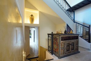 Uma escadaria com elegantes grades pretas e um armário decorativo com padrões elaborados.