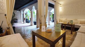 A hotel lobby with a reception desk, a seating area with a sofa, and a decorative wall. - RIAD BIJOUX (Marrakech)