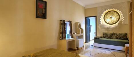 A bedroom with a bed, a desk, a chair, a sofa, and a decorative wall piece.