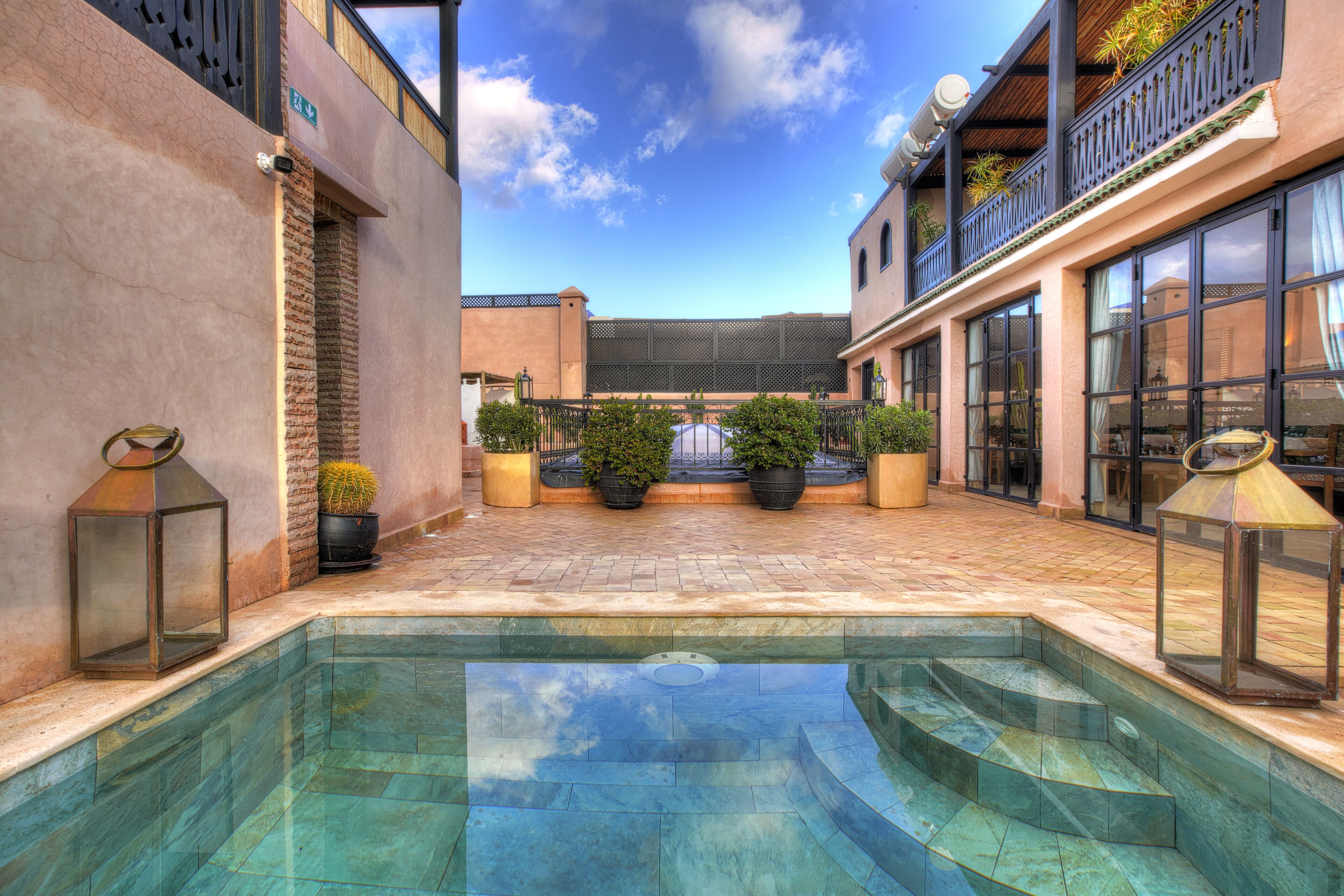 Un espace piscine avec des marches menant à l’eau, entouré de plantes en pot et de mobilier d’extérieur.