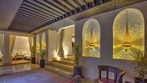A luxurious lobby with a patterned carpet, a seating area with a chair and table, and decorative wall lighting. - RIAD BIJOUX (Marrakech)