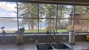 A kitchen with a large window overlooking a lake and forest.