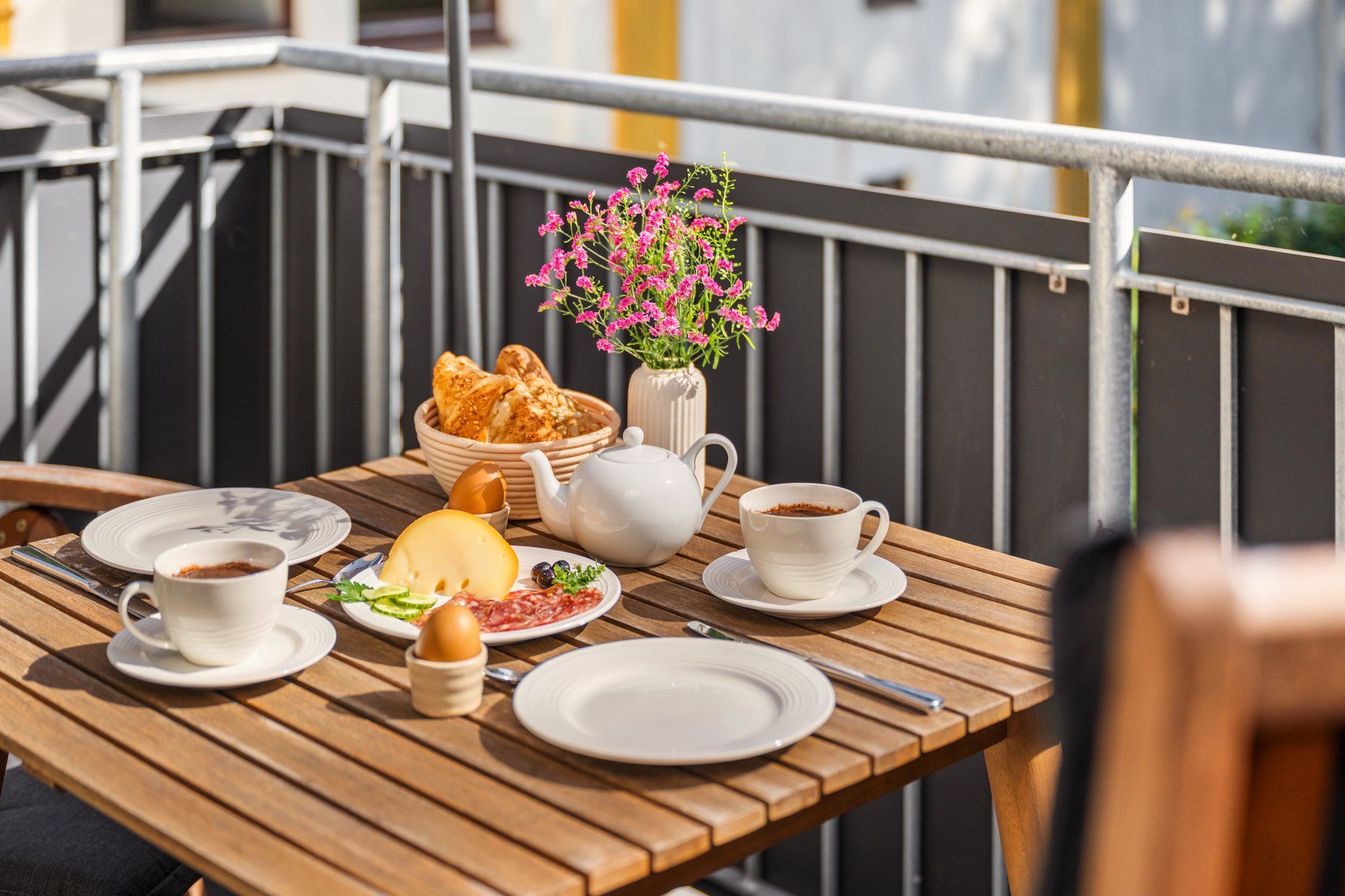 Een houten tafel met ontbijtartikelen zoals brood, kaas en een kop koffie.