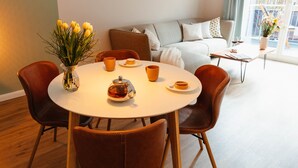 A modern dining area with a round table, brown chairs, and a pendant light. - Apartment between forest and lake with free-standing bathtub and balcony (5 star DTV) (Ratzeburg)