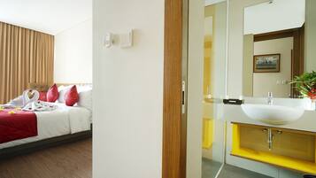 A hotel room with a bed, a bathroom with a sink and mirror, and a wooden door.