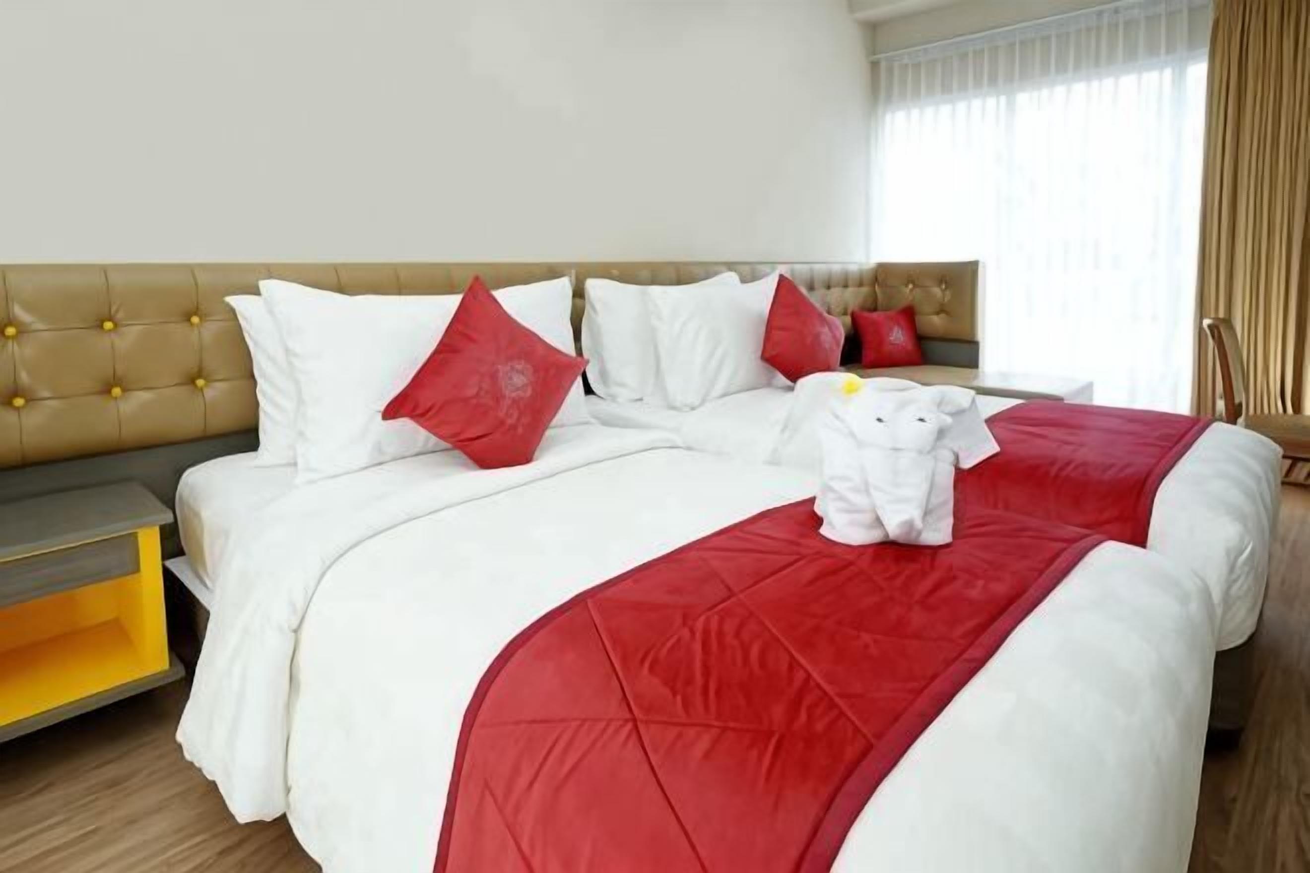 A hotel room with a bed, a nightstand, and a window with curtains.