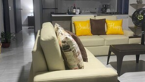 Una sala de estar moderna con un conjunto de sofás, una mesa de centro y una cocina al fondo.