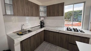 Una cocina moderna con un lavamanos integrado, una cafetera y un ventanal con vistas a un paisaje verde.