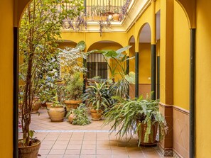 Un cortile dalle pareti gialle con piante in vaso e pavimento piastrellato.