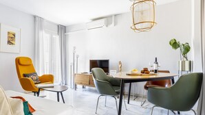 Un soggiorno moderno con zona pranzo, dotato di un divano, poltrone, un tavolo da pranzo e una lampada a sospensione.
