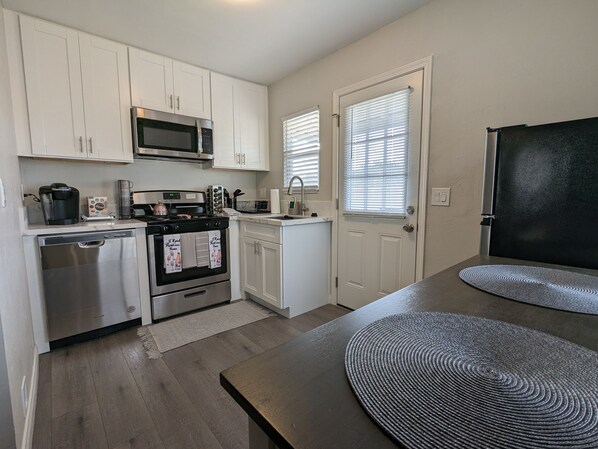 Compact kitchen with modern appliances, cabinetry, and a large table.