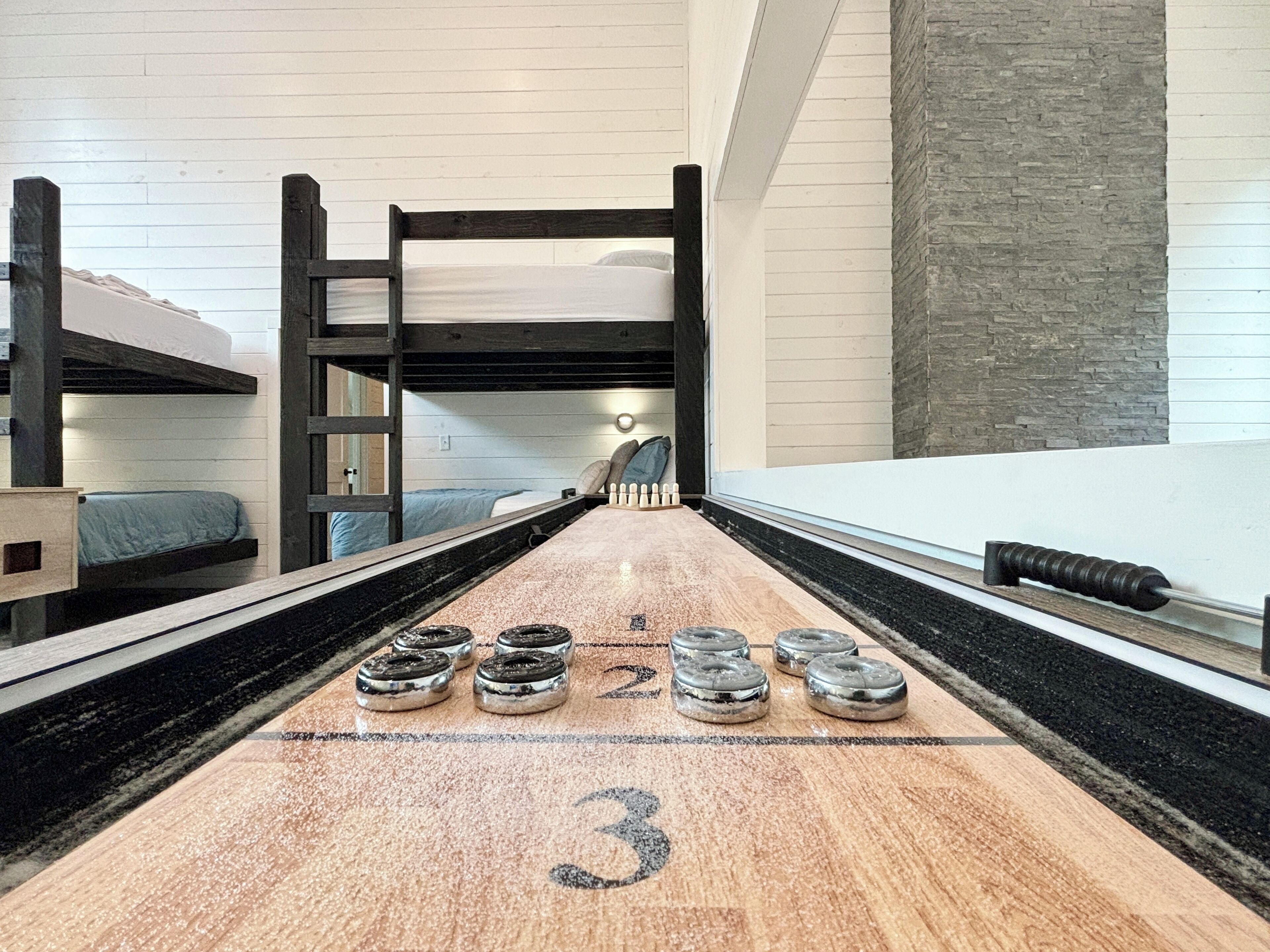 A bunk bed room with a shuffleboard table.