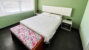 A bedroom with a bed, a bench, a nightstand, and a window. - Apto a 5 min de la playa, Platja d'Aro (Platja d'Aro)