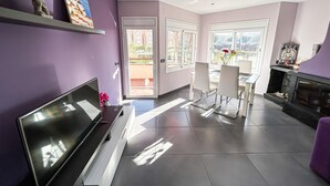 A modern living room with a flat-screen TV, a fireplace, and a dining area with chairs. - Apto a 5 min de la playa, Platja d'Aro (Platja d'Aro)