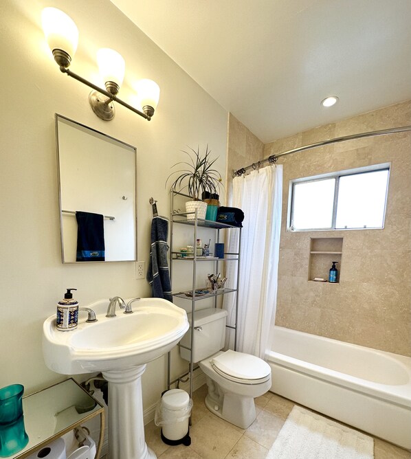 A bathroom with a pedestal sink, a toilet, a bathtub, a shower curtain, and a window. - Near Water Garden Tech Hub ✧ Walk to Metro ✧ 2BR + 2 Parking (Santa Monica)