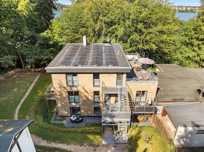 A modern building with a flat roof, solar panels, and a patio area with outdoor furniture. - Vacation apartment between forest and lake with two terraces (Ratzeburg)