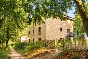 A building with a wooden facade, a dirt path leading to it, and a wooden fence surrounding the property. - Vacation apartment between forest and lake with two terraces (Ratzeburg)