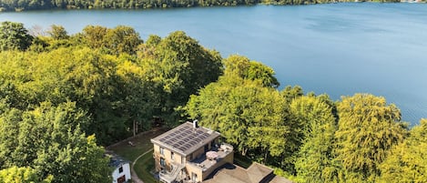 A lakeside property with a main building featuring a sloped roof and a solar panel array.