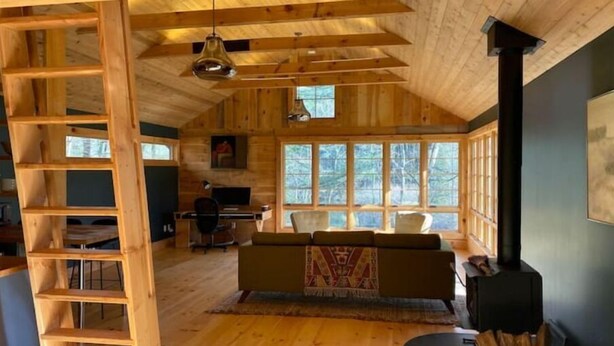 Ein gemütliches Blockhaushaus-Interieur mit Holzausstattung, Kamin, Schreibtisch und einer Couch.