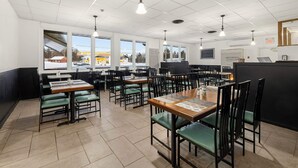 Un restaurant spacieux, doté de nombreuses tables et chaises, de grandes fenêtres et d’un intérieur propre et moderne.